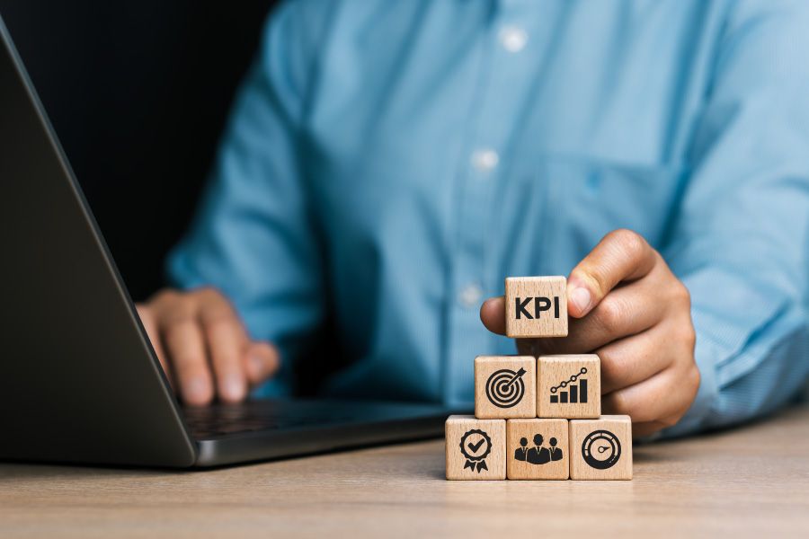Businessman con Laptop e dadi con icone KPI