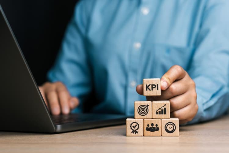 Businessman con Laptop e dadi con icone KPI